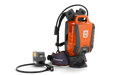 Side view of a Husqvarna battery backpack with a connected charger.