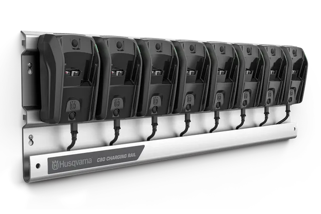 A Husqvarna charging rail with eight battery chargers mounted on it.