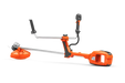 Side view of a Husqvarna brush cutter with ergonomic handles and cutting head.